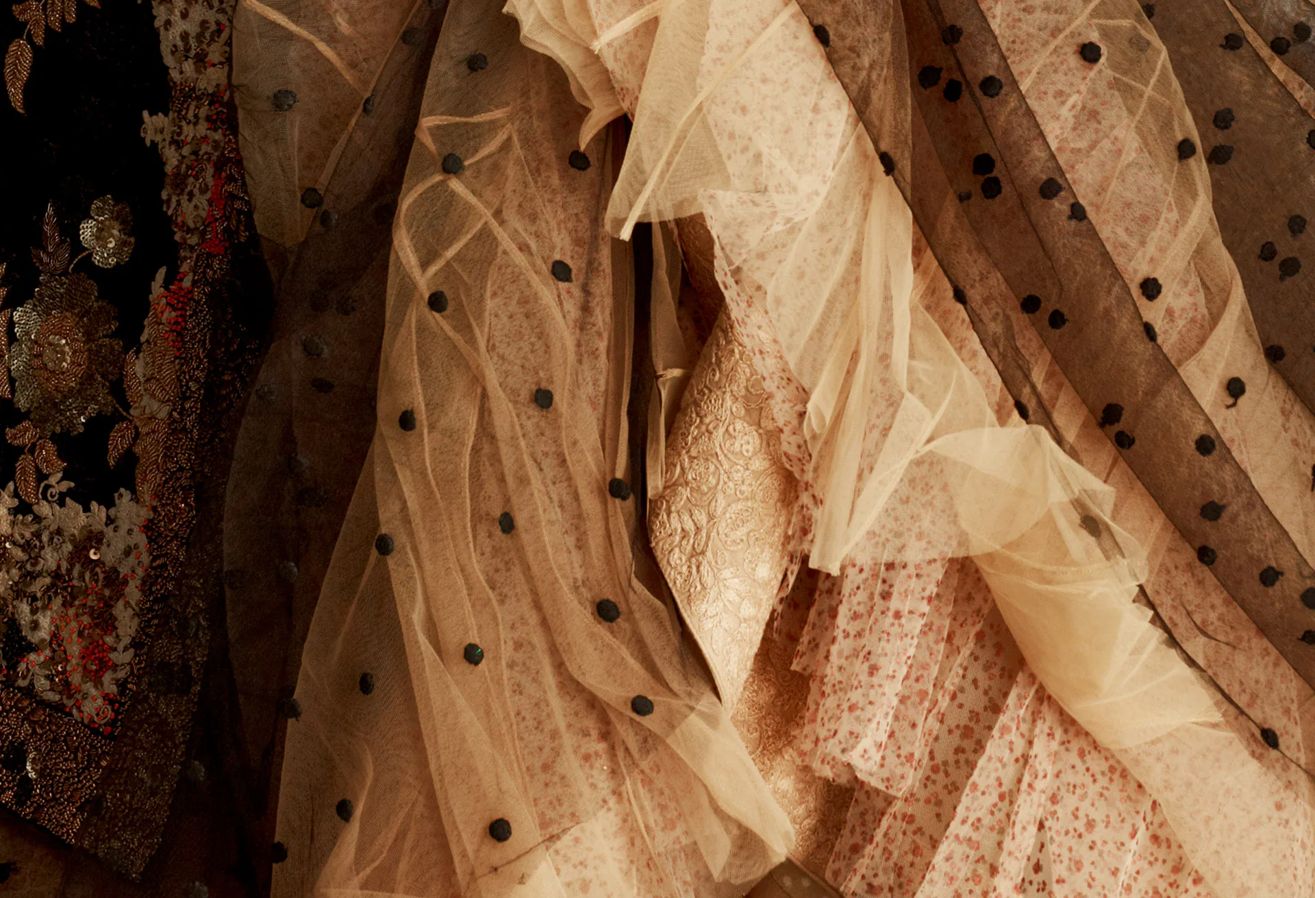 A detail of embellished tulle, dotted net lying over lace and beadwork.