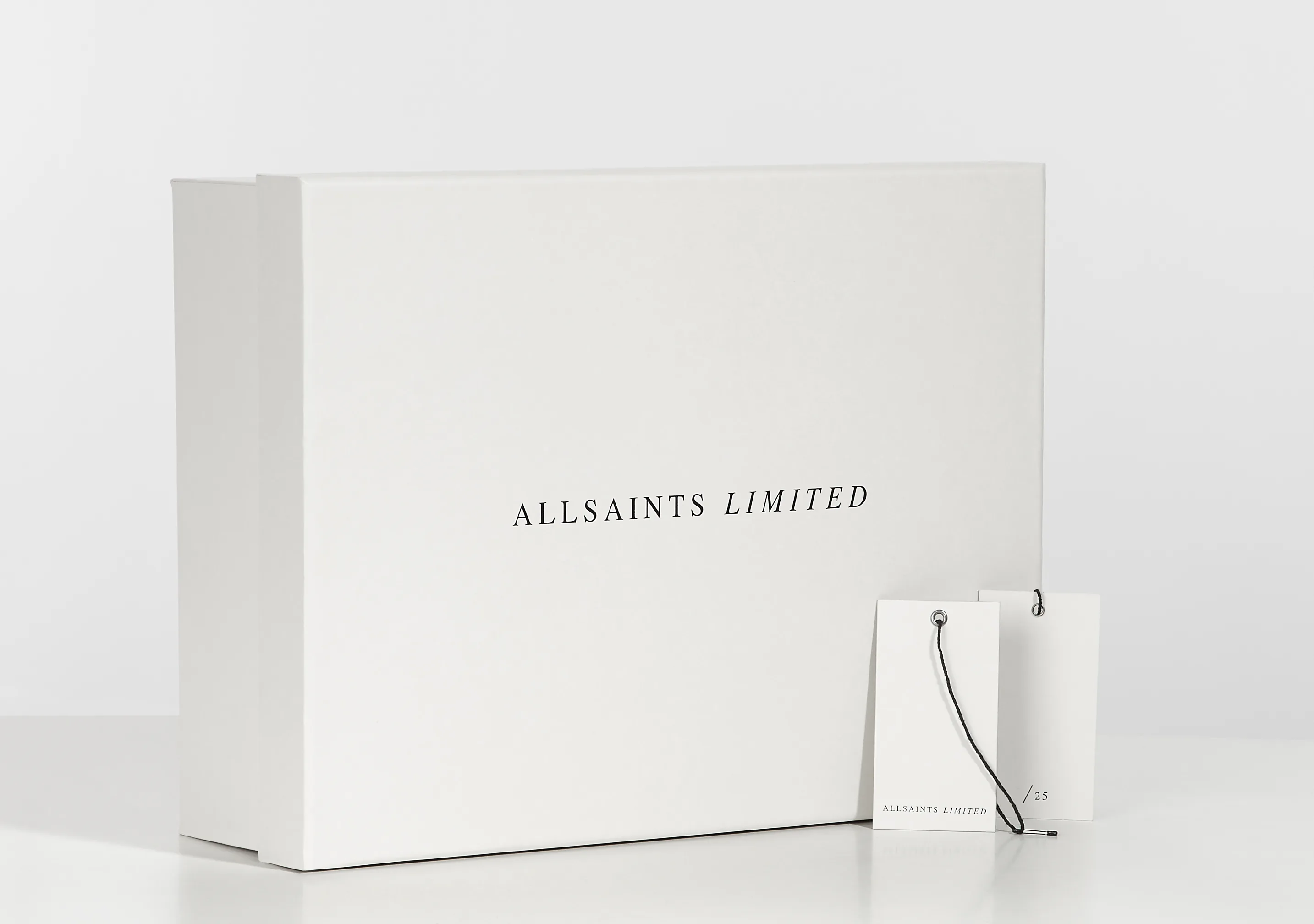 A white AllSaints Limited box with a swing tag beside it.