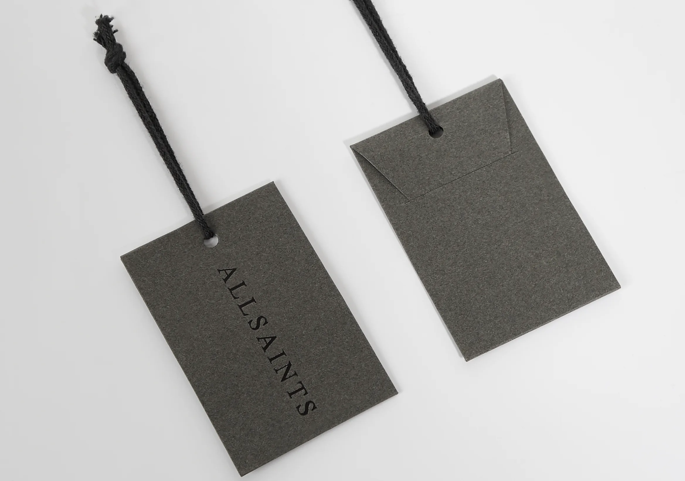 Two dark AllSaints swing tags hanging on cords.