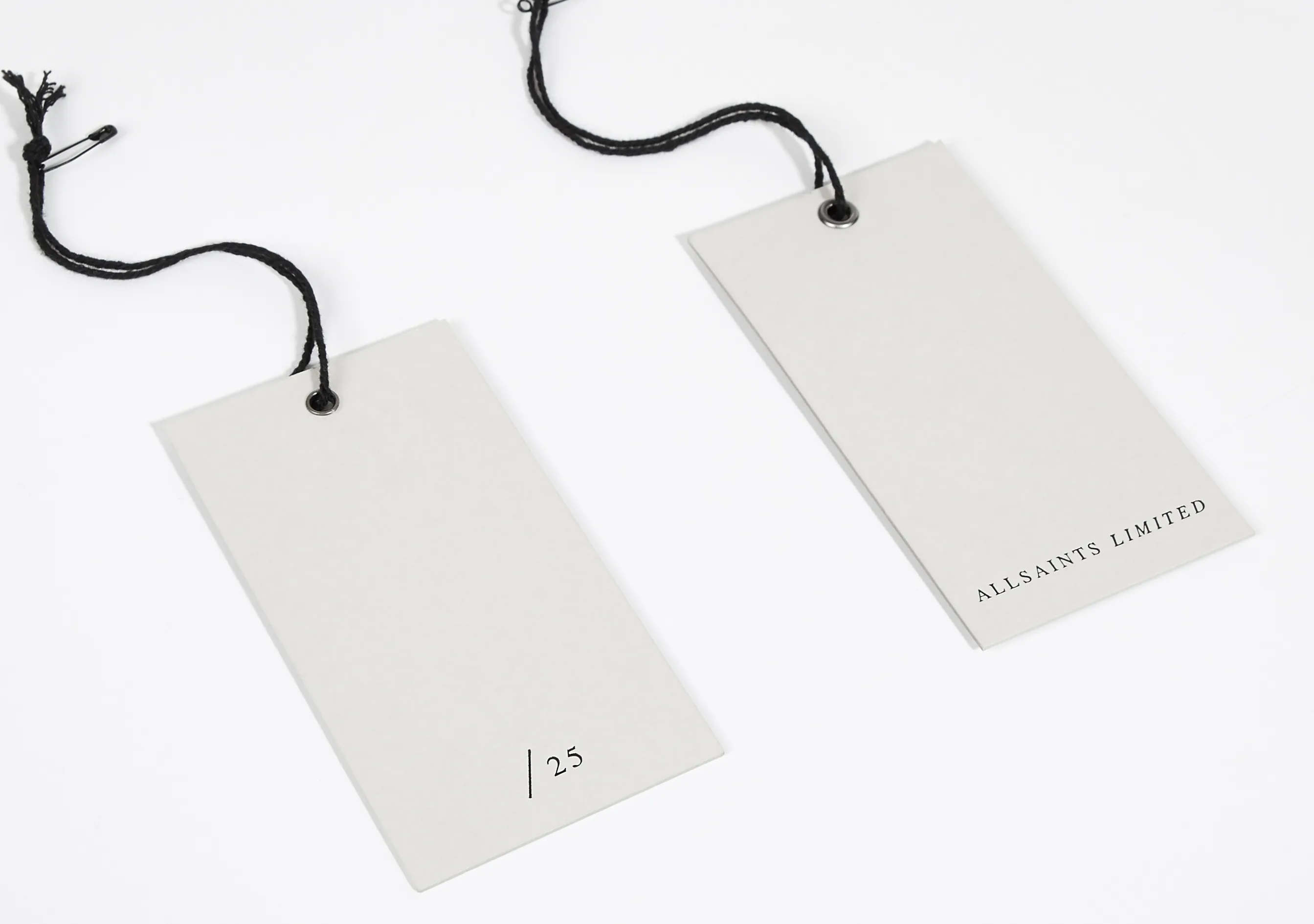 Two pale AllSaints Limited swing tags hanging on cords.