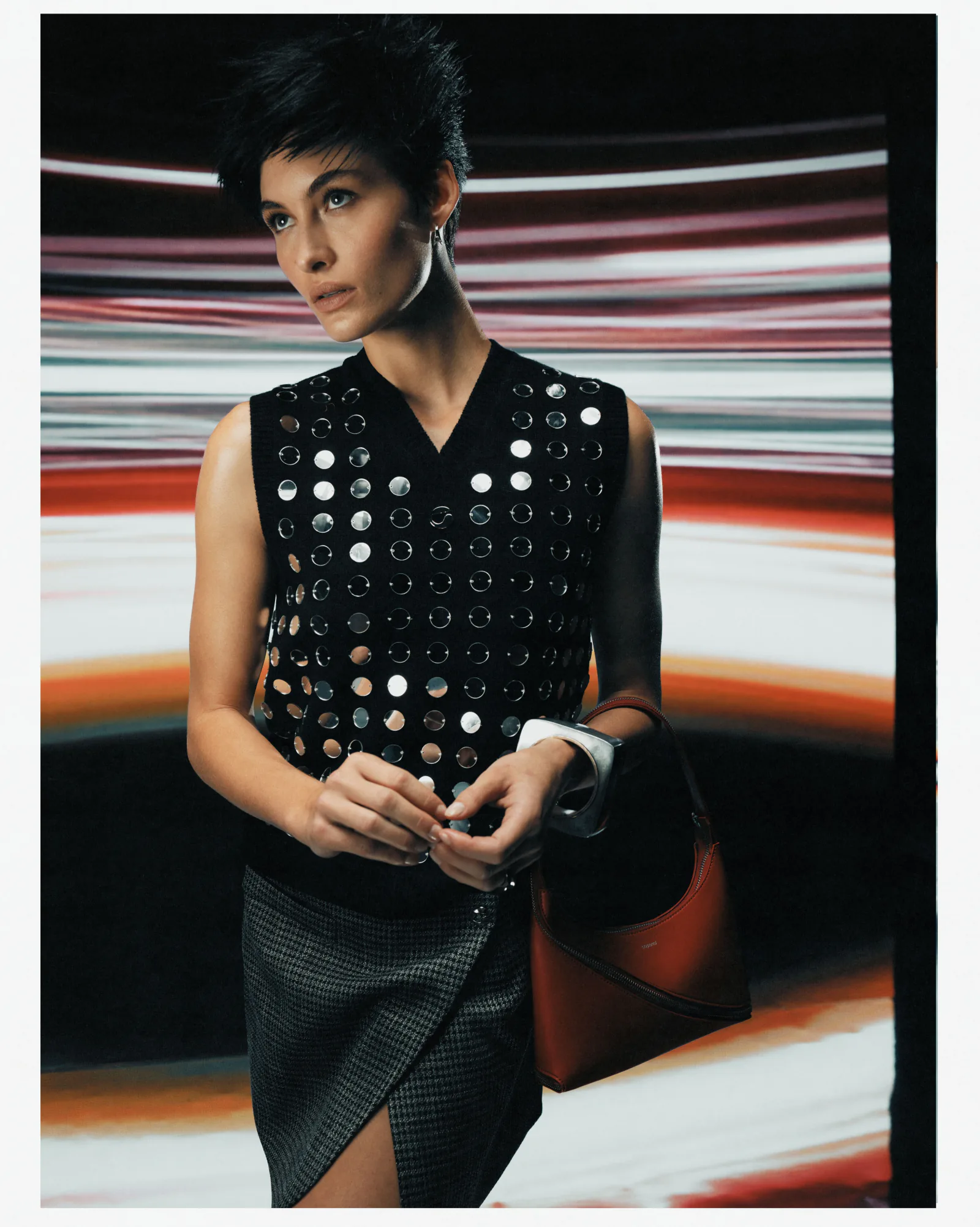 A woman in a black perforated top against streaks of coloured light.