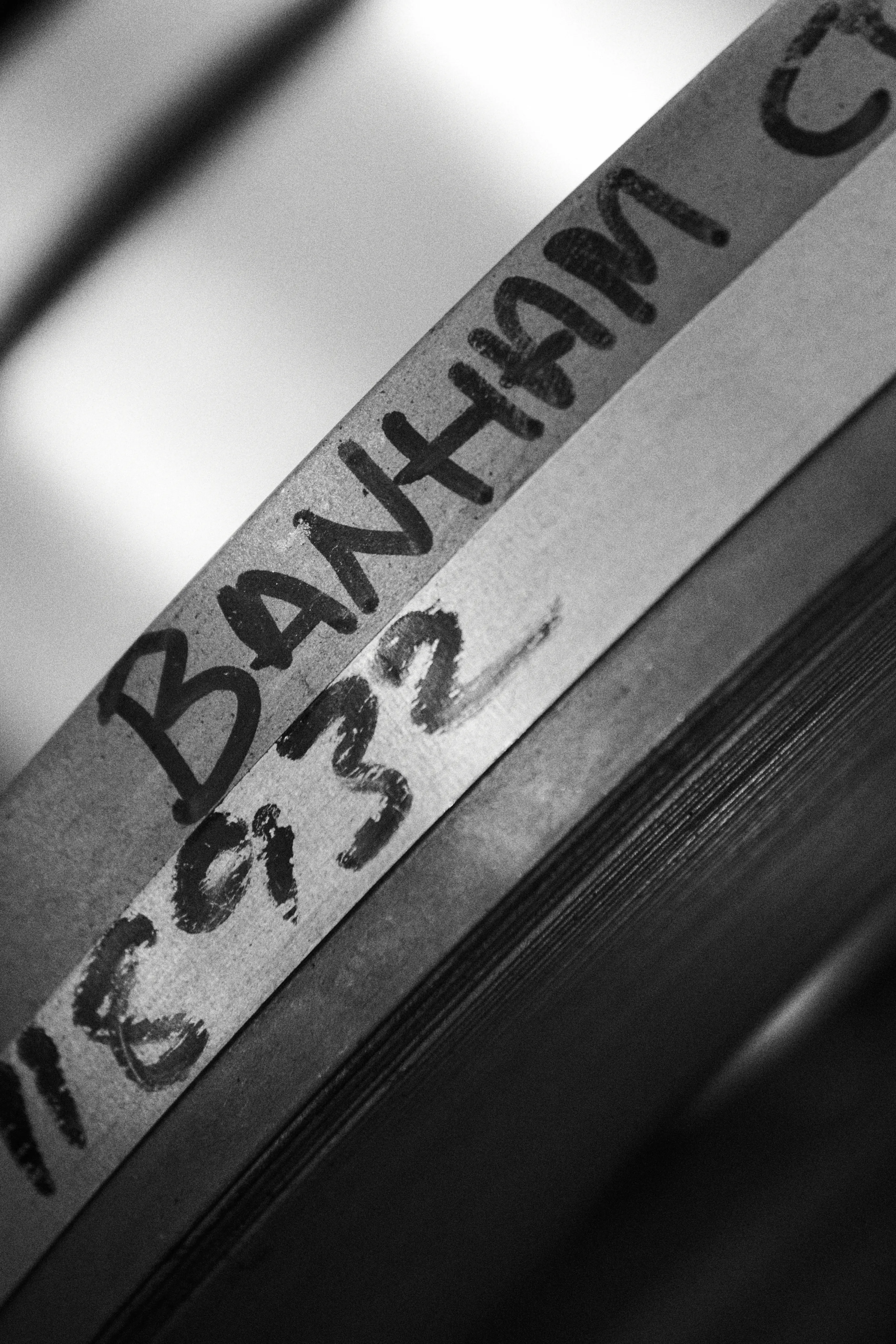 A tape label marked BANHAM in pen along the edge of a stack of sheet metal.
