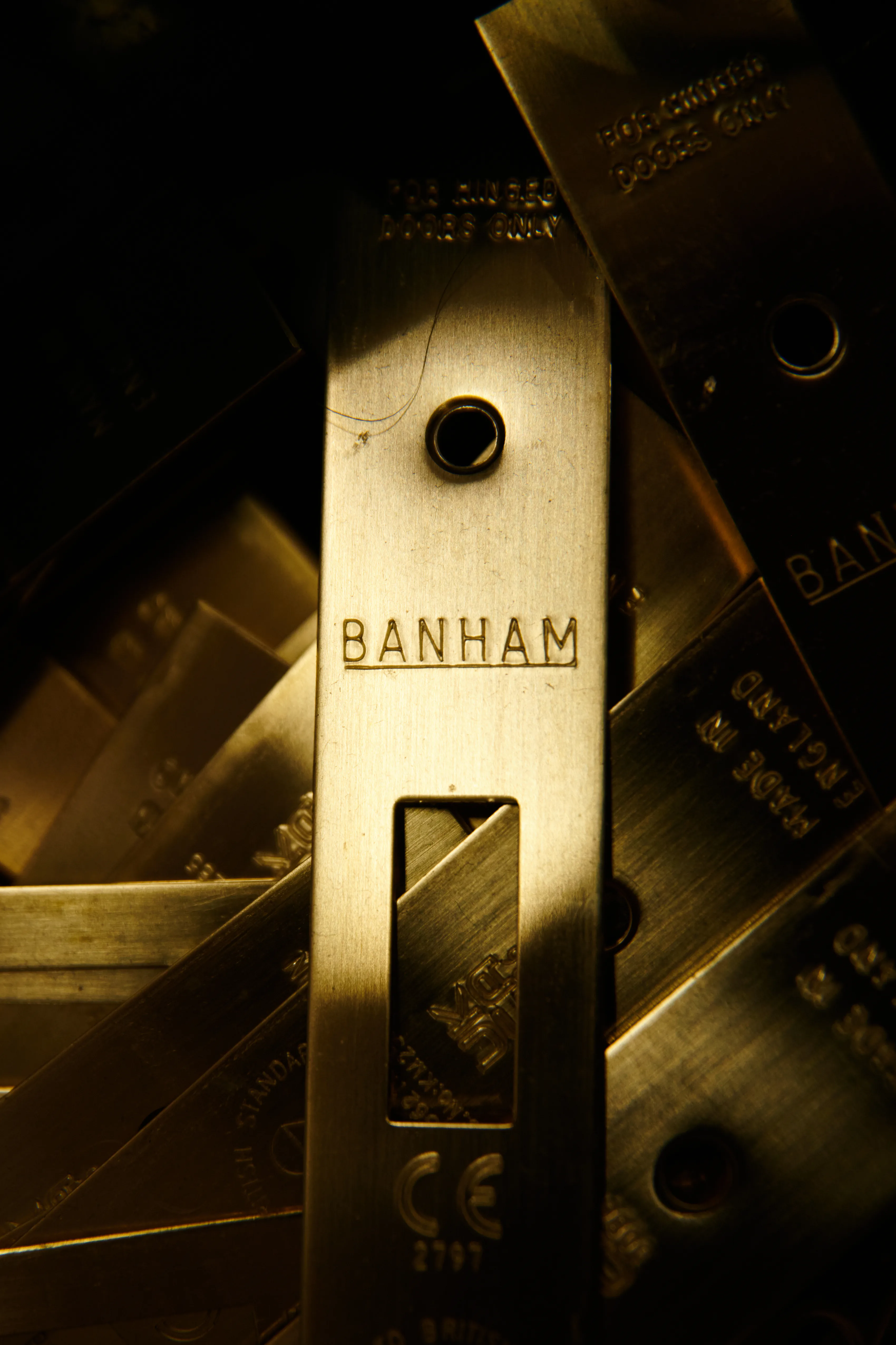 Brass Banham striking plates heaped together, the one in the light engraved with the Banham name, a kitemark and a CE mark.