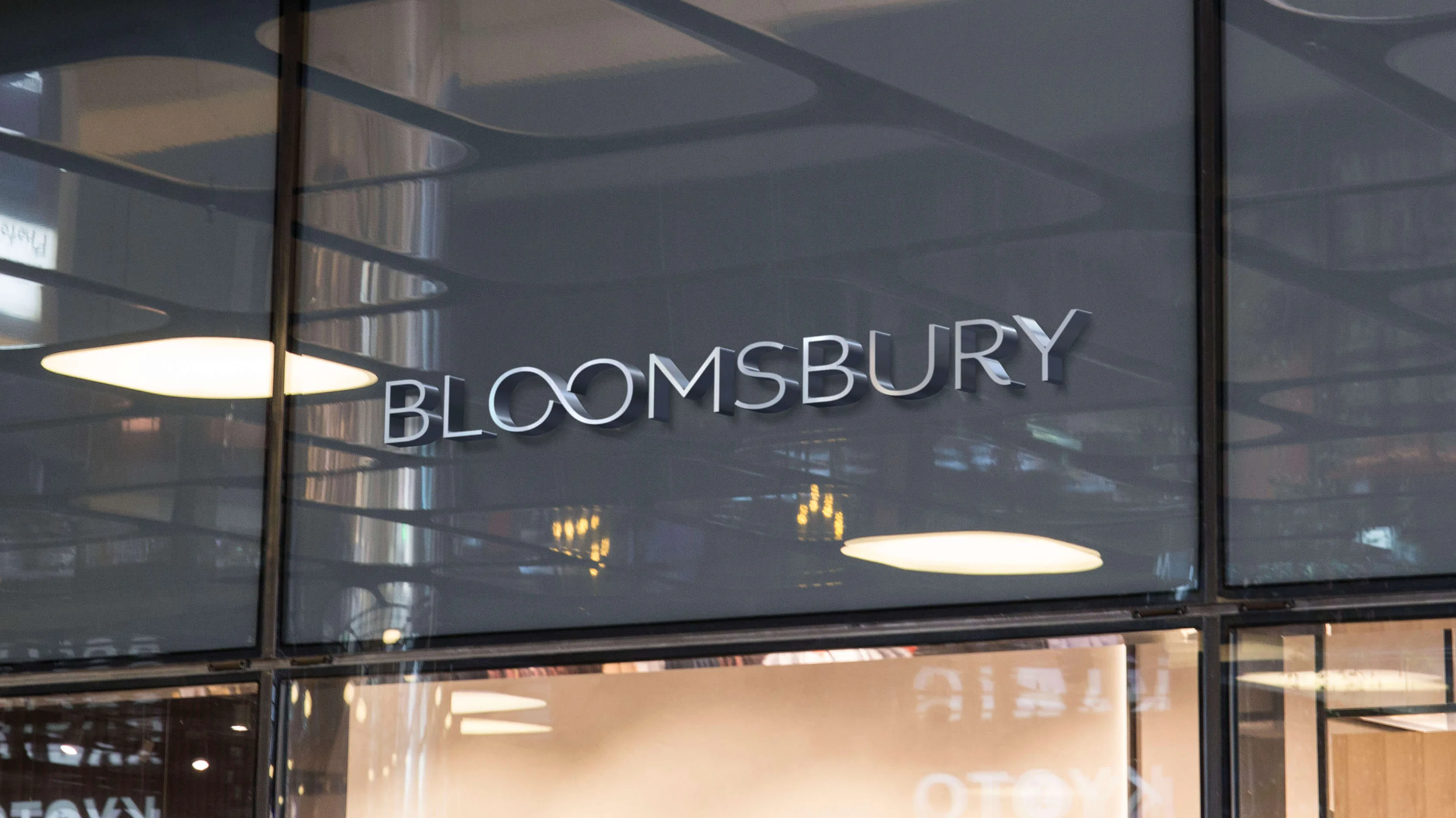 The BLOOMSBURY shopfront sign in brushed steel letters on dark glazing, lit by two pendant lights.