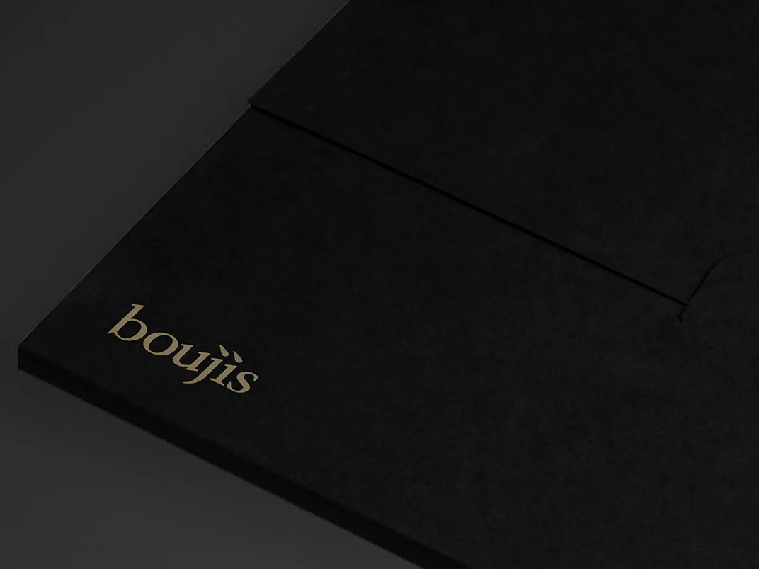 A black menu cover, the boujis wordmark blocked in gold at its corner.