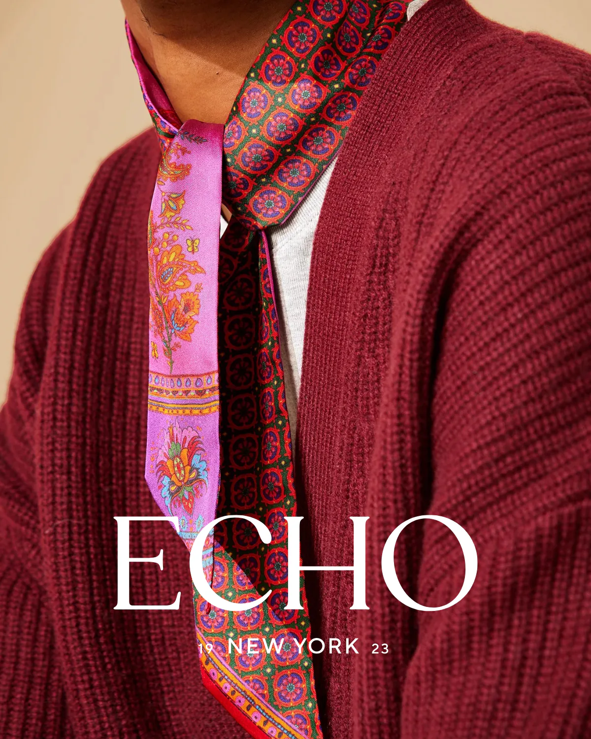 A pink patterned scarf at the neck of a burgundy cardigan, under the ECHO New York lockup.
