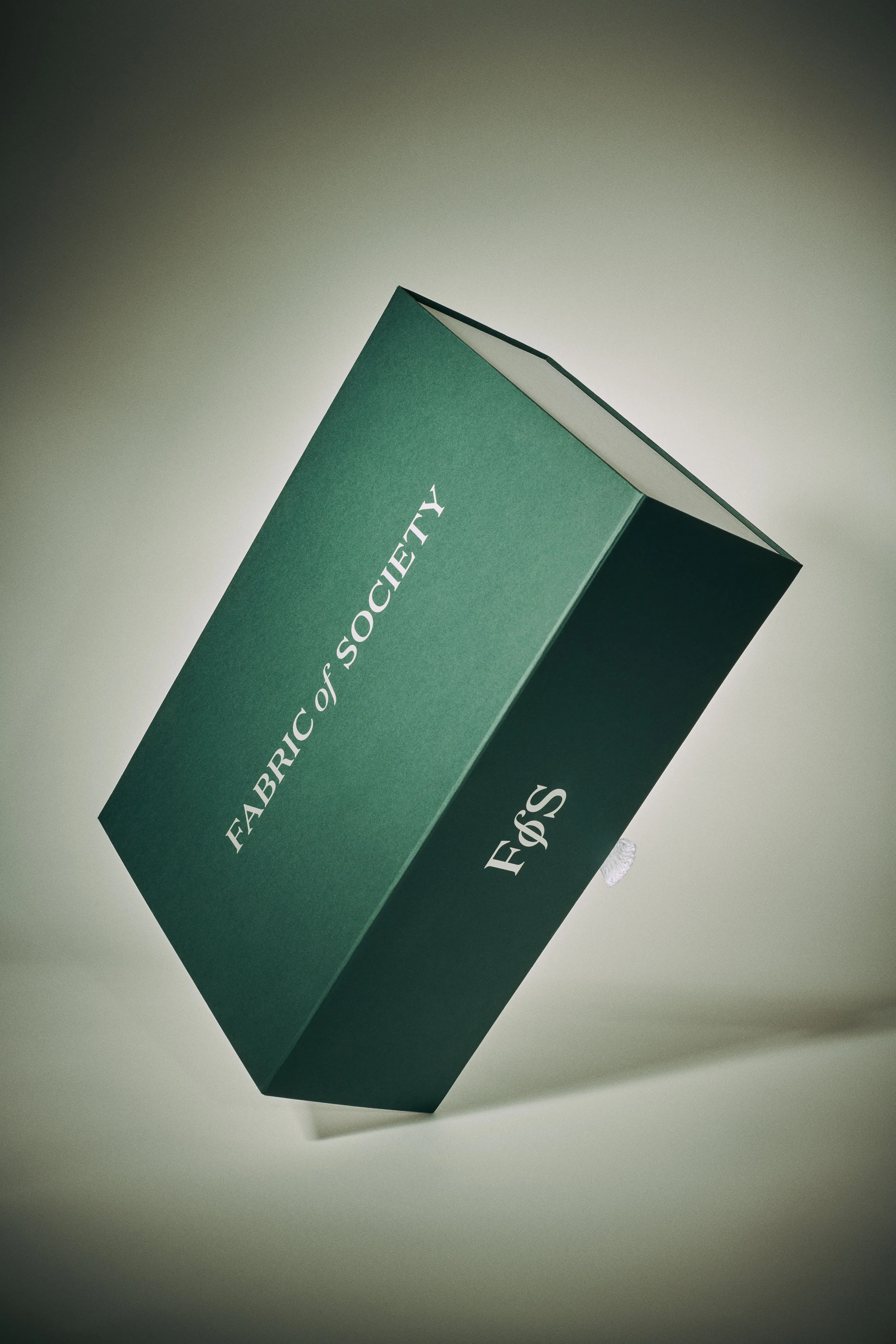 A green Fabric of Society box, photographed at an angle.