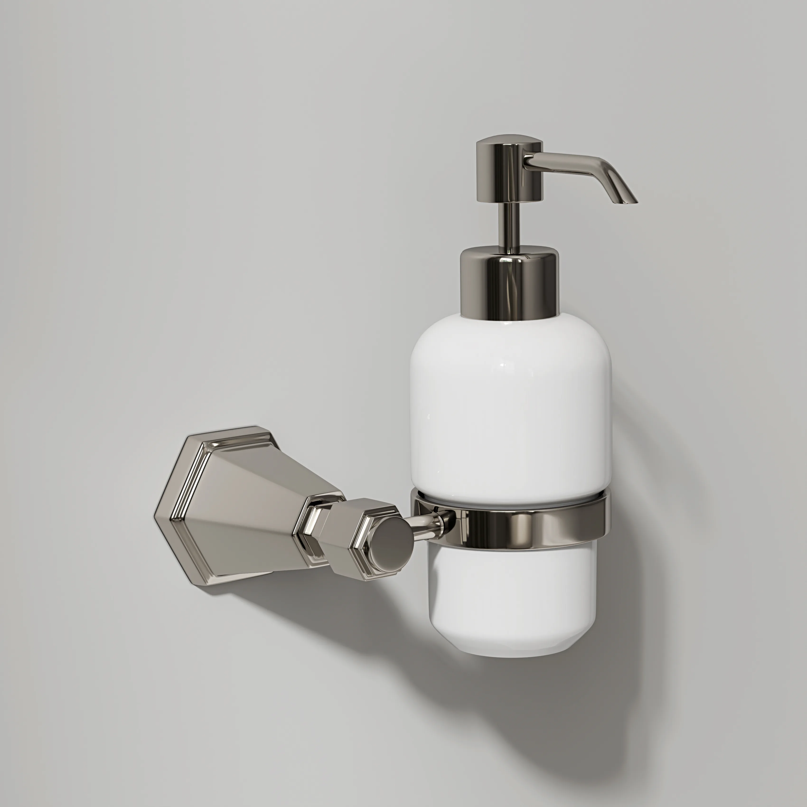A wall-mounted nickel holder cradling a white ceramic soap dispenser.