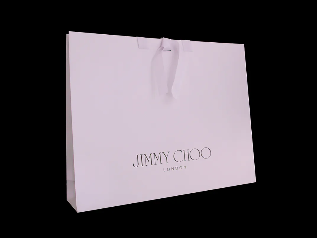 A white Jimmy Choo carrier bag with ribbon handles.