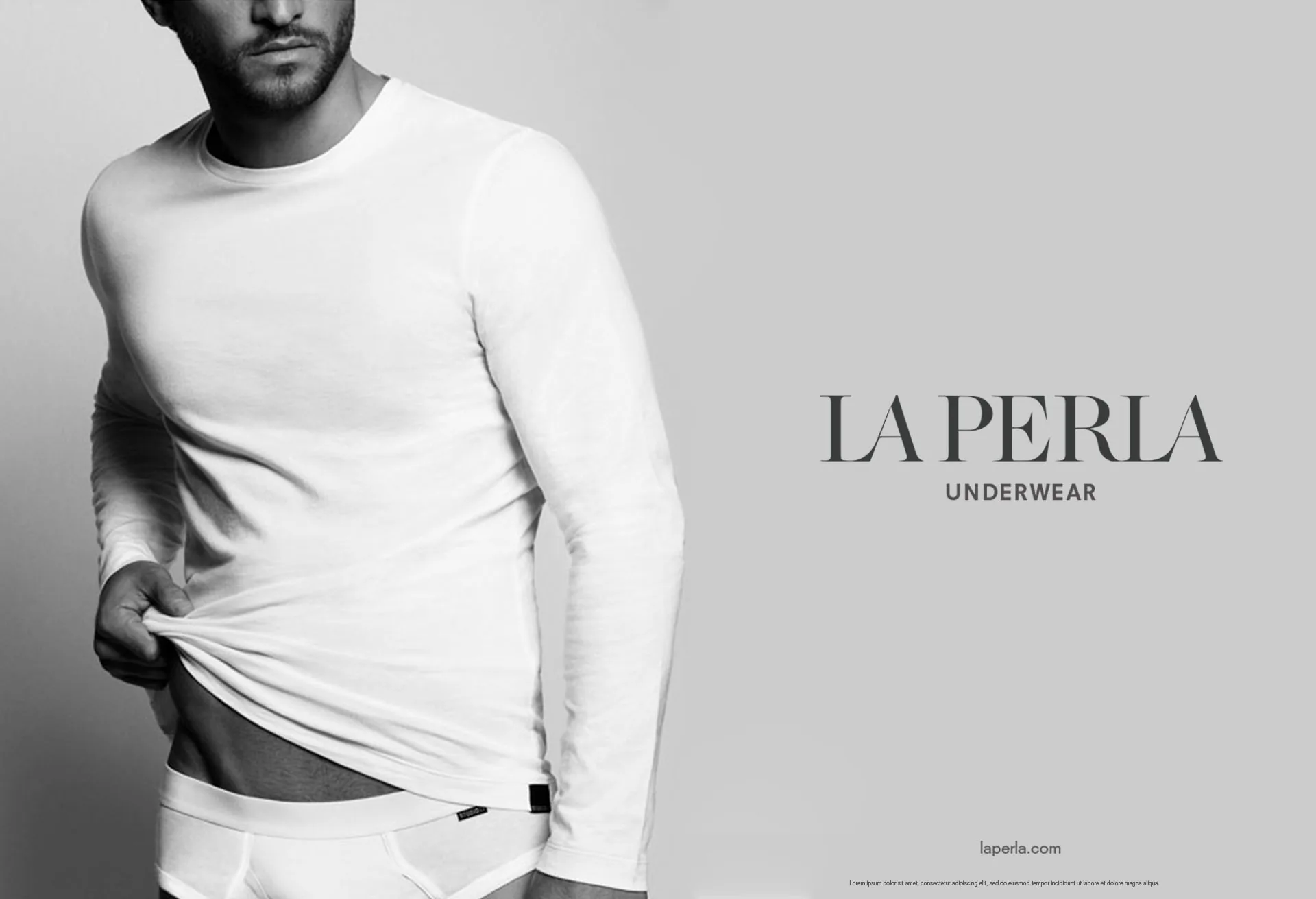 A black and white underwear campaign image, a man in a white long-sleeved top beside the La Perla Underwear wordmark.