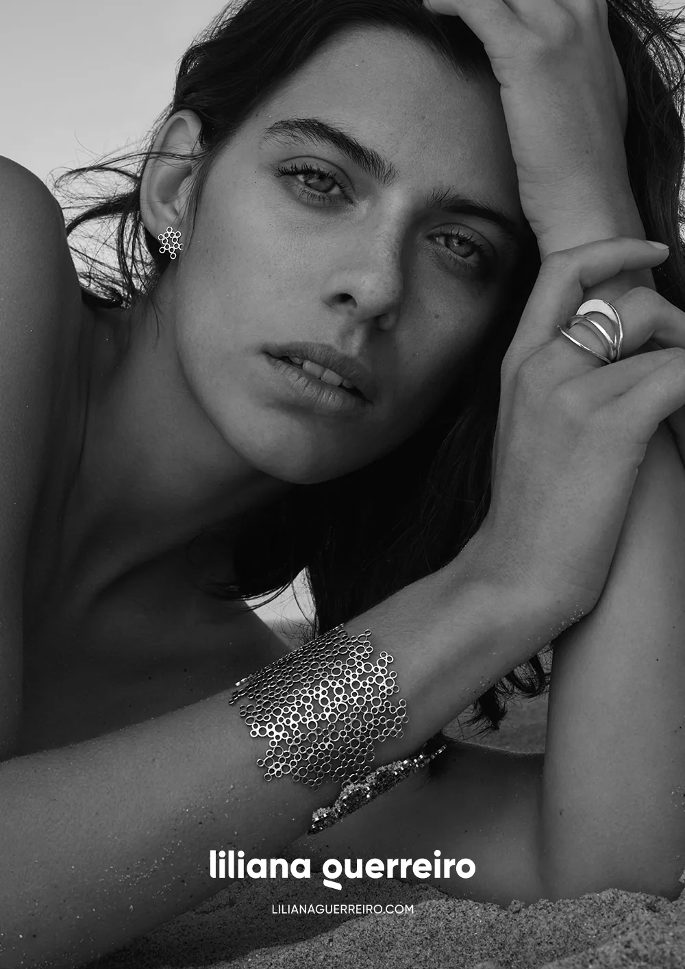 A black and white campaign portrait, an arm raised to show a ring and a filigree cuff.