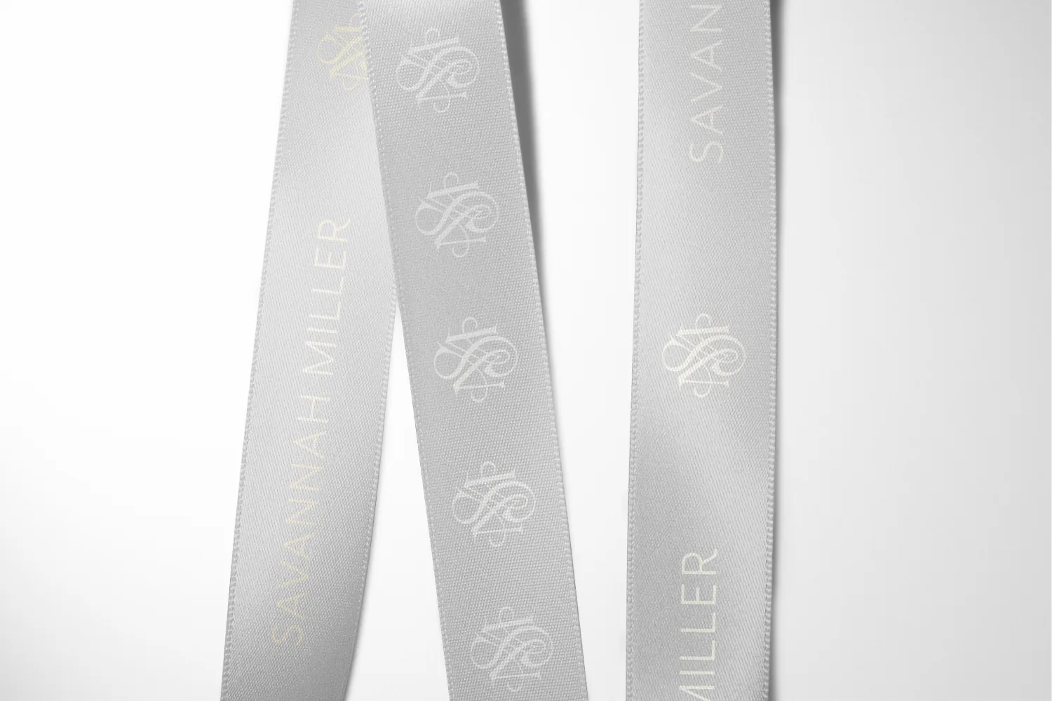 Printed ribbon carrying the Savannah Miller name and monogram, folded on white.
