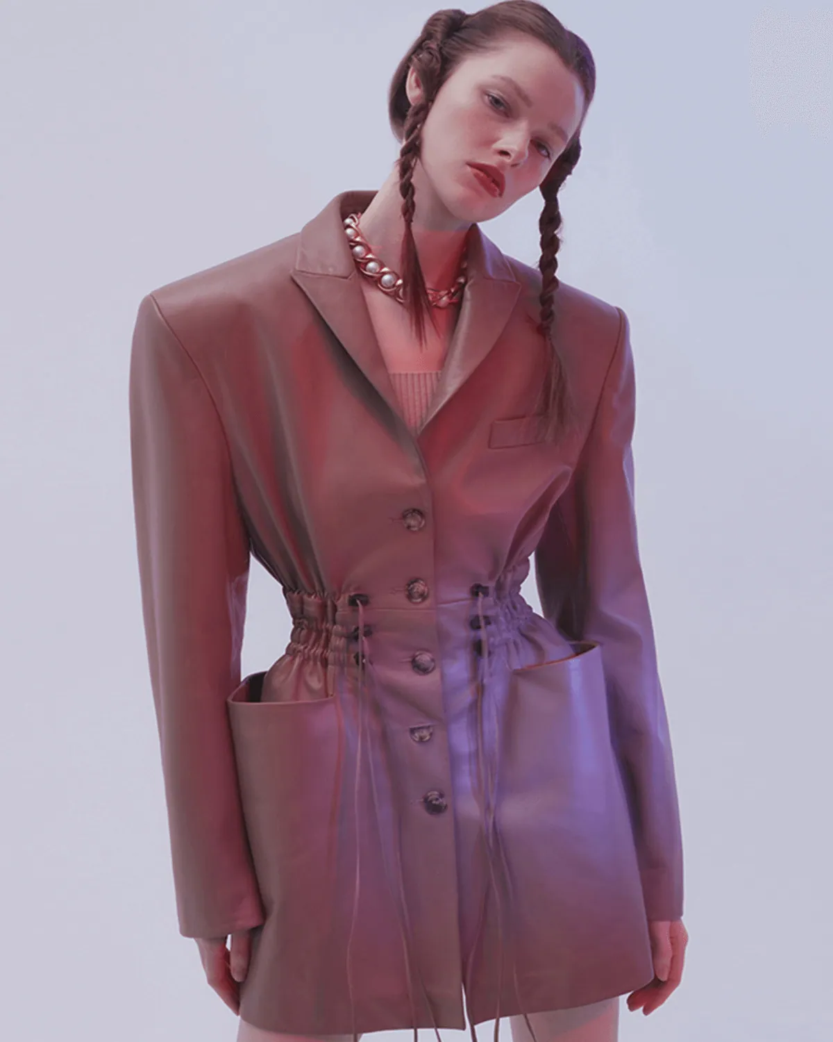 A model with plaited hair in a lilac leather trench coat.
